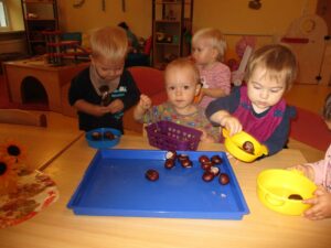 Gruppe kleiner Kinder spielen mit Kastanien