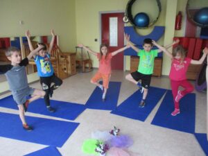 Kinder im Turnraum stehen auf einem Bein
