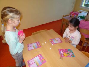 2 Mädchen spielen mit Würfeln am Tisch