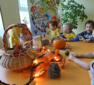 Kinder sitzen am Tisch mit einem Kürbis in der Mitte