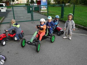 Kinder auf Tretautos mit Helmen