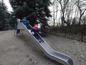Kinder rutschen eine silberne Rutsche runter