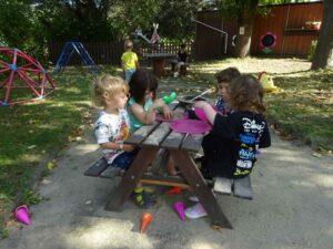 4 Kinder draußen sitzend spielen mit Sand