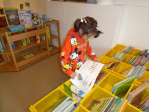 ein Mädchen stöbert in Kisten mit vielen bunten Büchern