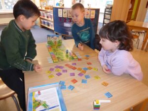3 Kinder spielen ein Brettspiel