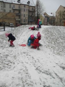 mehrere Kinder rutschen verschneiten Hügel herunter