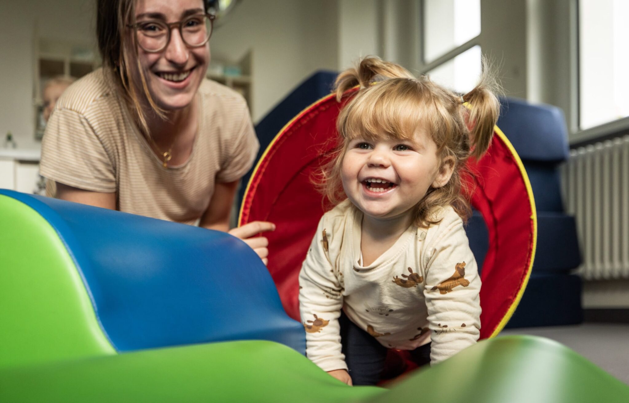 ein kleines Mädchen krabbelt durch eine Röhre und lacht