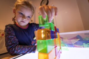 ein Mädchen stapelt bunte Bausteine