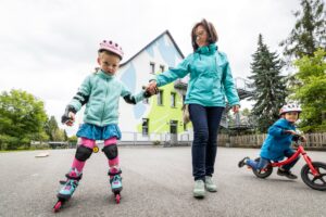 Kind mit Rollerblades mit Erzieherin an der Hand