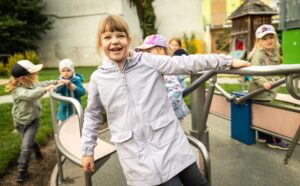 mehrere Kinder auf Sitzkarussell auf Spielplatz