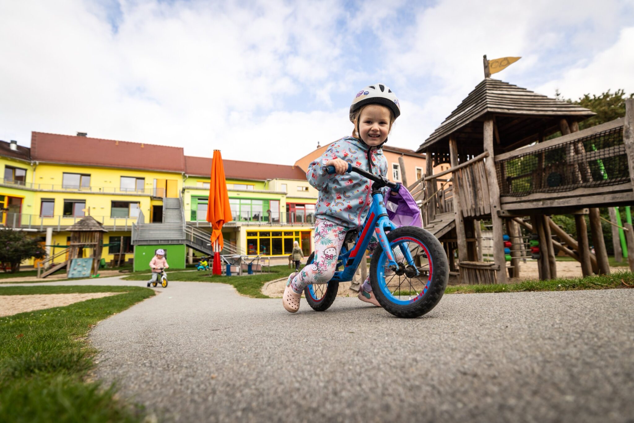 ein Kind mit Laufrad auf dem Spielplatz