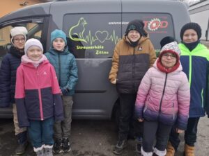 Kinder posieren vor dem Auto der Streunerhilfe.