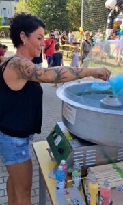 Eine Mutter fertigt lachend Zuckerwatte an.