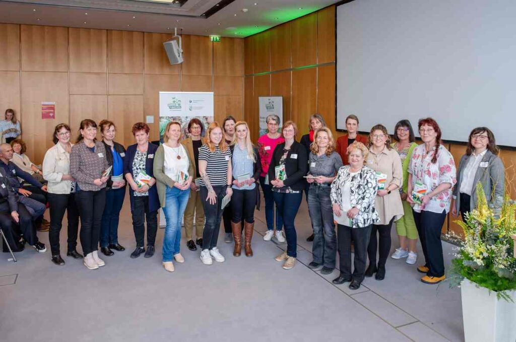 Gruppe von Menschen aufgestellt für ein Gruppenfoto vor einer hölzernen Wand.